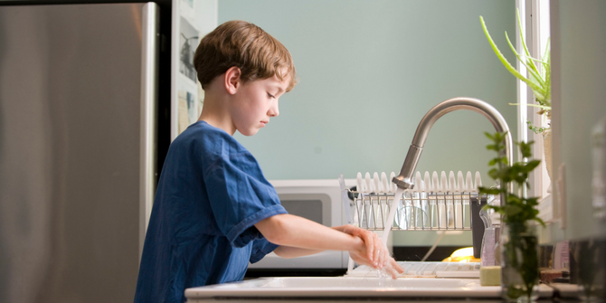 Child washing their hands at the kitchen sink